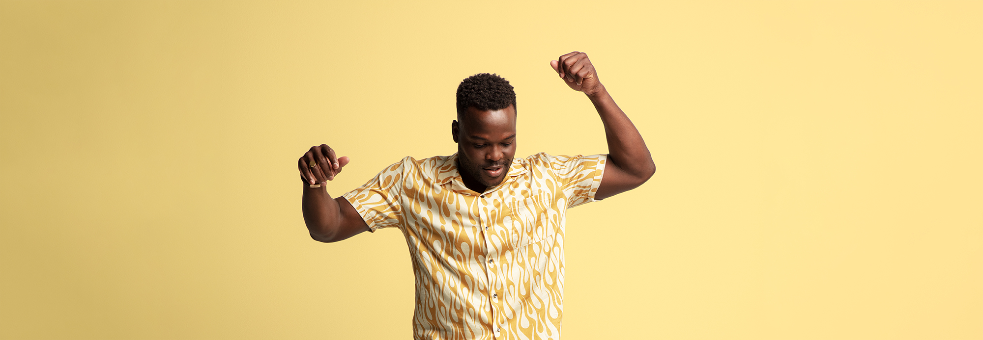 A man wearing a yellow and white flame-patterned shirt striking a pose